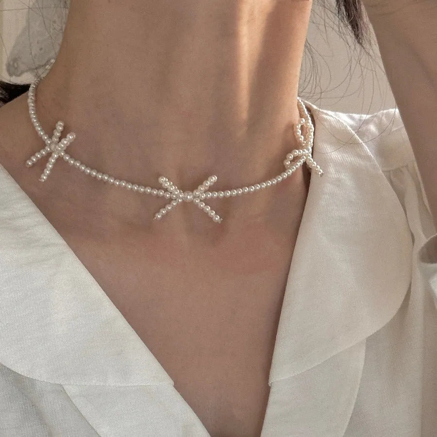 White bow pearl necklace with geometric clasp on woman at clavicle length