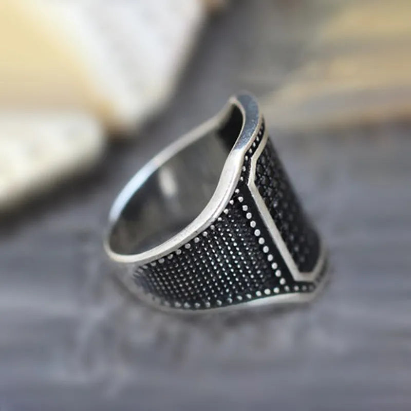 Close-up of a black alloy ring with a copper inlay stripe and sparkling clear zircon stones on a finger.