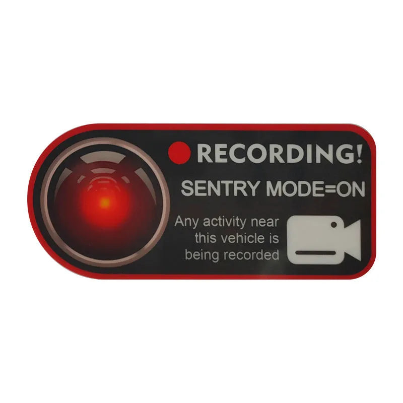 A pair of white rectangular Tesla Sentry Mode warning stickers with black text, measuring 11cm by 5cm.