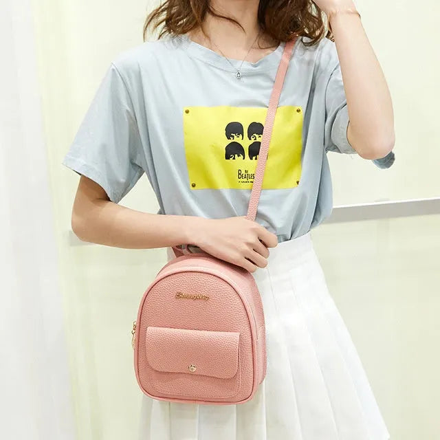 Small black PU leather women's shoulder backpack with zipper, shown next to a mobile phone.