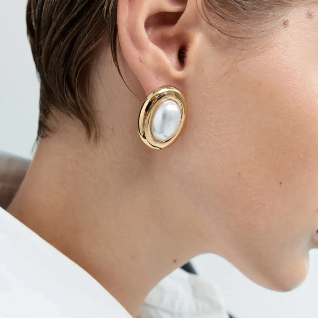 A pair of stainless steel vintage pearl stud earrings for women with a post-back closure.