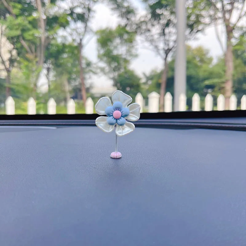 Small colourful plastic swing ornament for car dashboard, shown in blue, green, pink, purple, and yellow.
