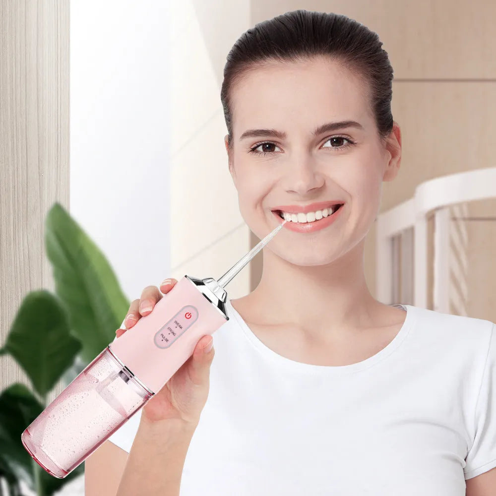Handheld electric water pick in white, pink or light green with three speed settings, under 300mL tank, USB cable and four nozzles
