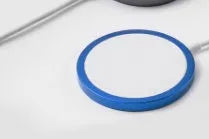 Silver metallic MagSafe-compatible magnetic wireless charger for iPhone on a wooden desk.