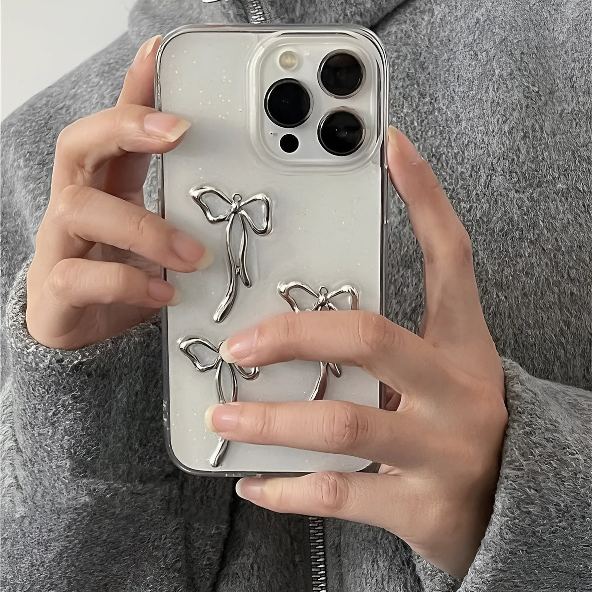Metal bow iPhone case with anti-drop function and 3D epoxy drip glue detail, available for iPhone 15, 14, 13, 12, and 11 models.