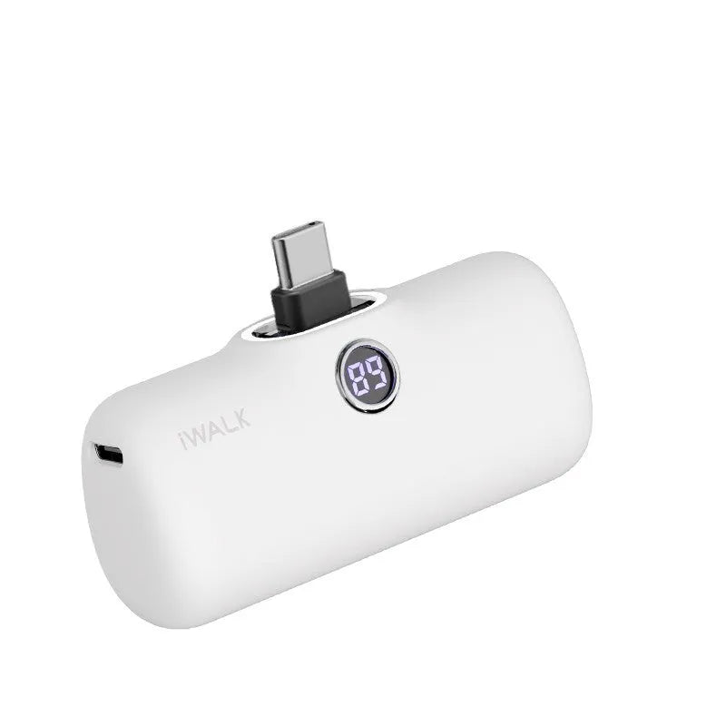 Small white lipstick-shaped power bank showing digital battery percentage display on a wooden table.