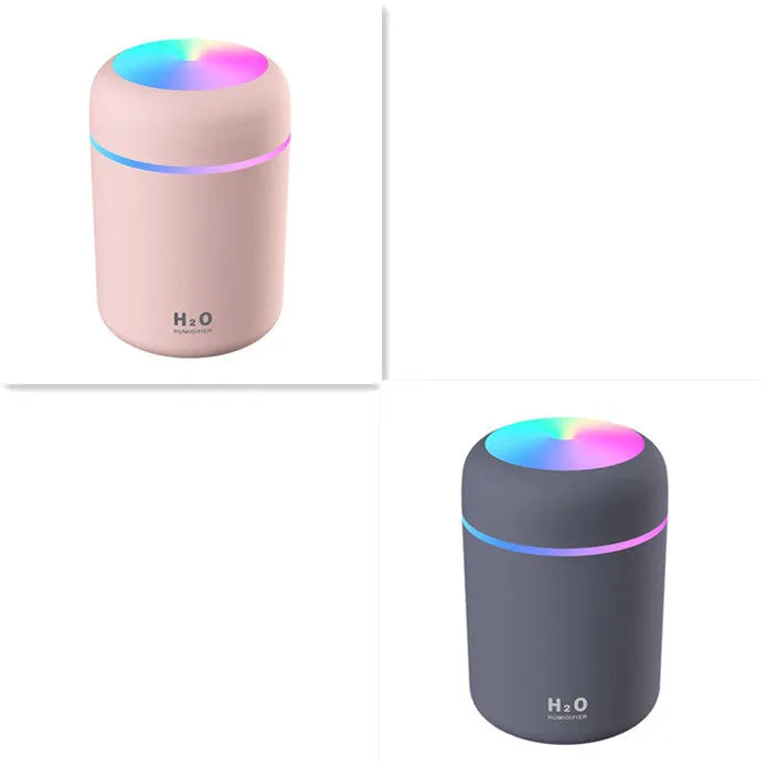 Pink USB mini humidifier with LED lights on wooden desk beside laptop