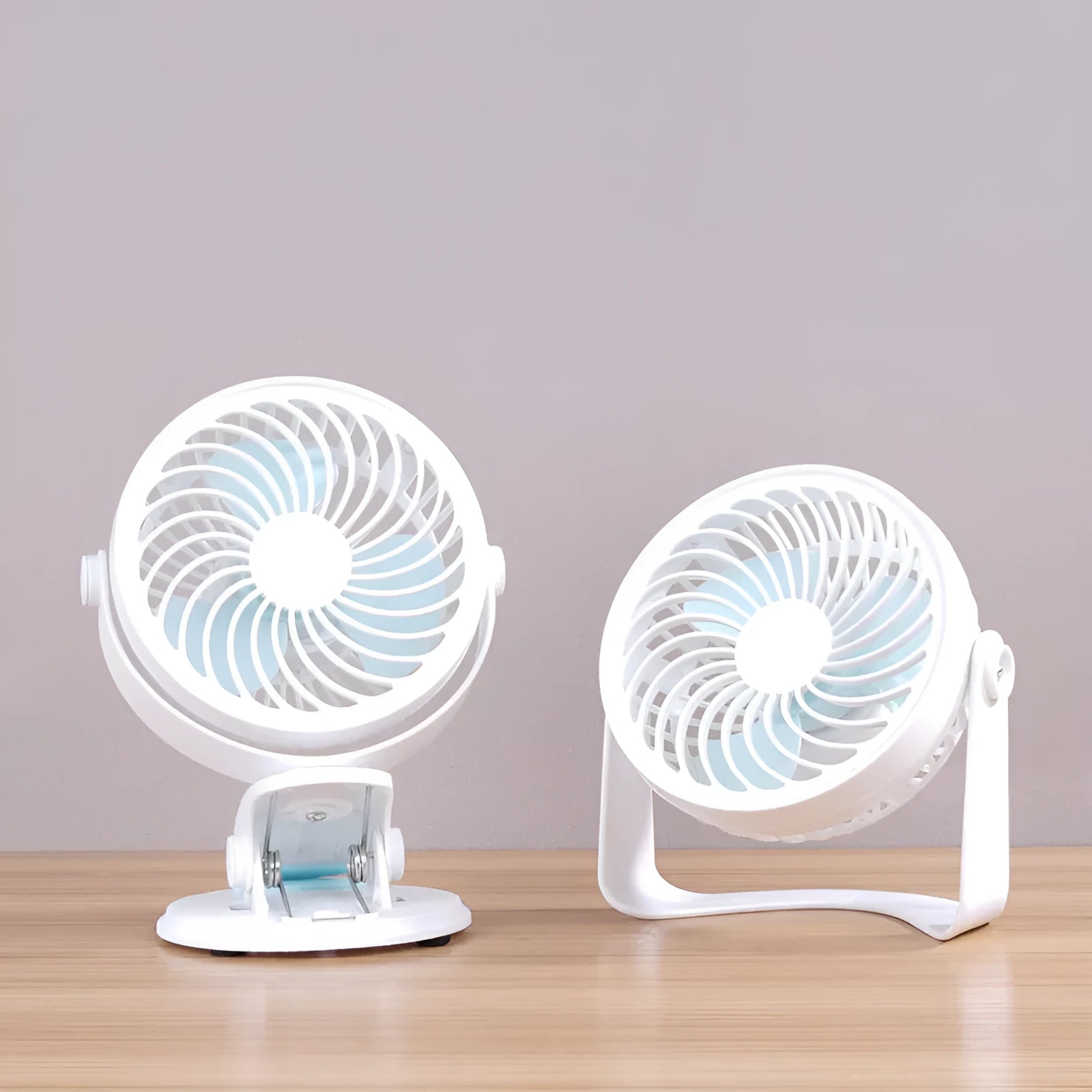 Small white USB desk fan with clip base and three blades on a wooden desk.