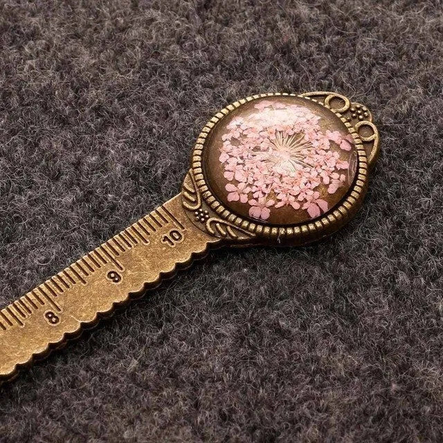 Handmade dried gypsophila and clover flower bookmark ruler on a book, showing 12cm length.