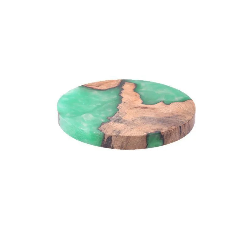 Round and square black and green resin coasters with wood texture for tea pots on a table.
