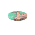 Round and square black and green resin coasters with wood texture for tea pots on a table.