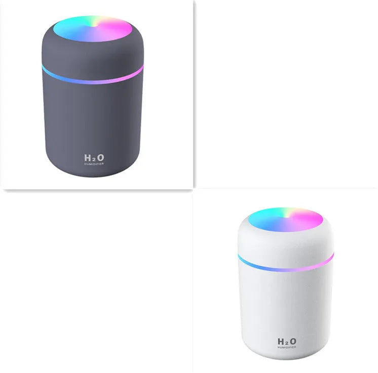 Pink USB mini humidifier with LED lights on wooden desk beside laptop