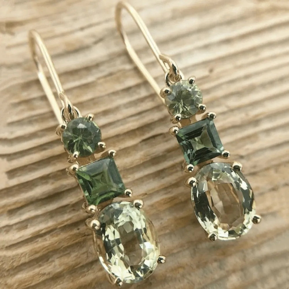 Green geometric copper earrings with a quadrilateral shape on a plain background.