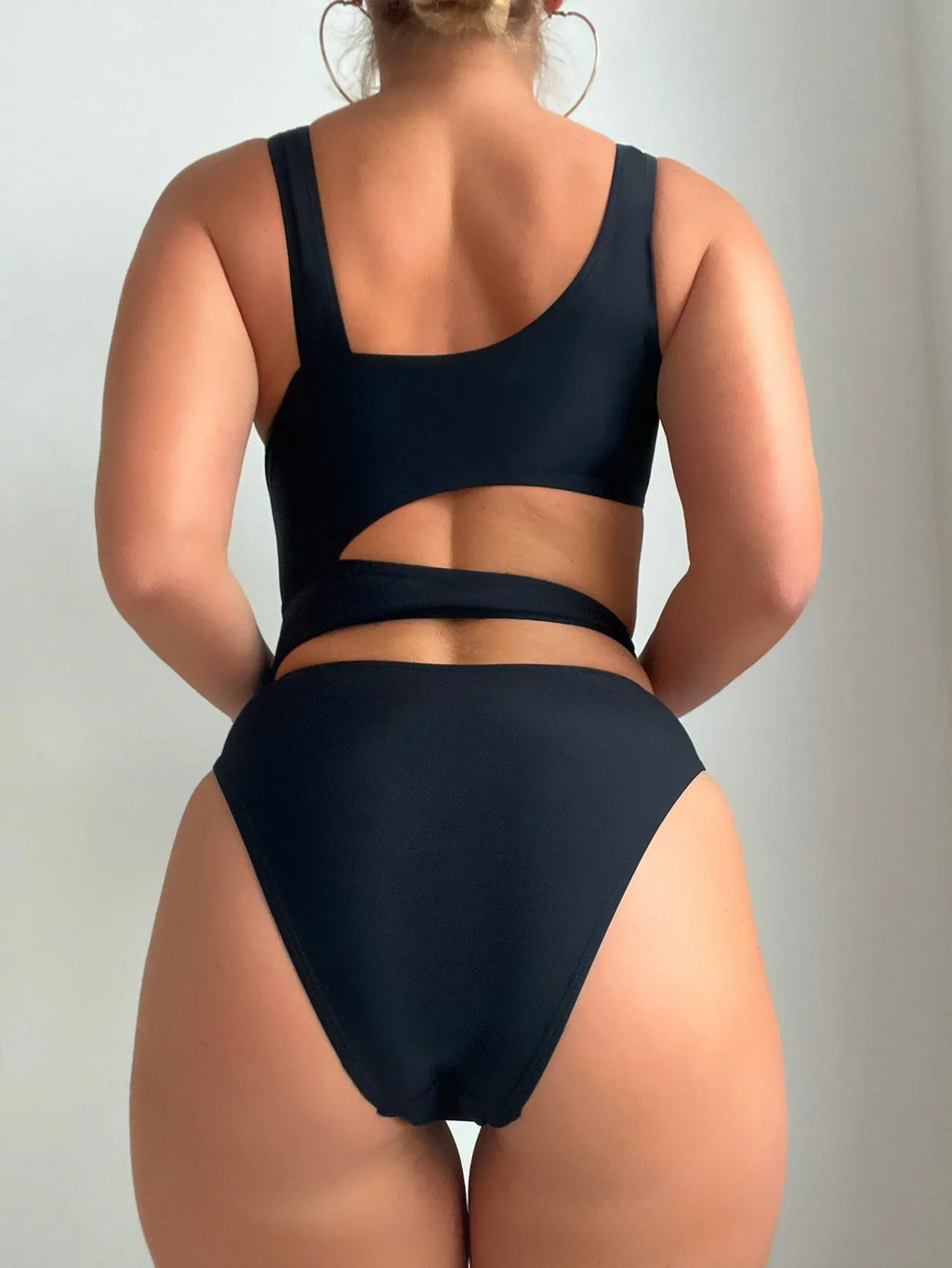 A solid black women's one-piece swimsuit with a high cut leg design on a mannequin.