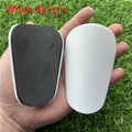 Extra small mini plastic football shin guards in black and white, shown at 8cm by 5cm size.