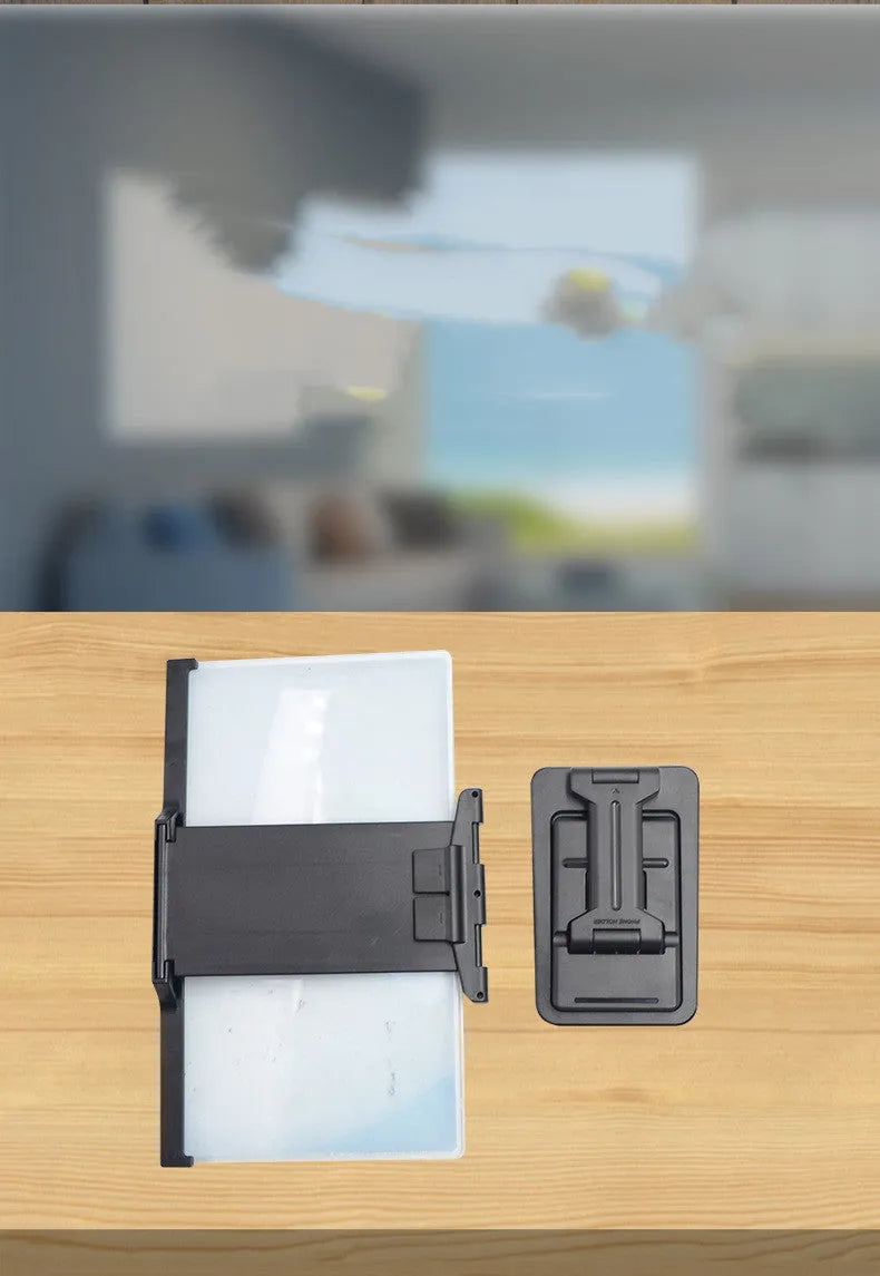 Black foldable mobile phone screen magnifier with detachable phone holder shown on a desktop.