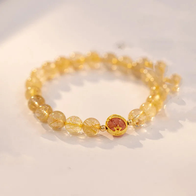Citrine gold rutilated quartz crystal bracelet with diamond-cut beads on a wrist.