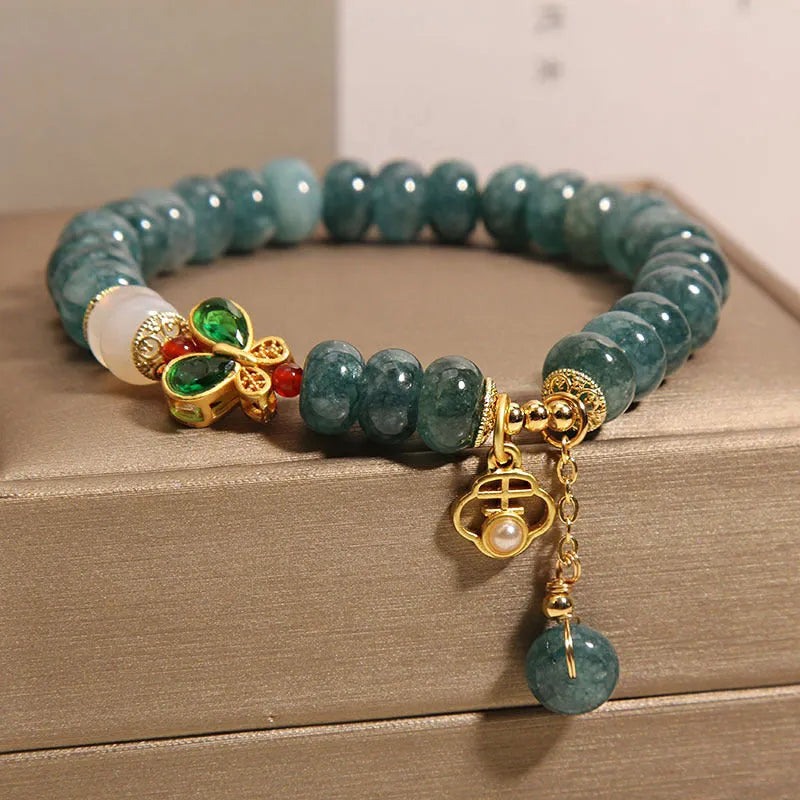 Blue water jade bead bracelet with white agate abacus beads and a butterfly charm.