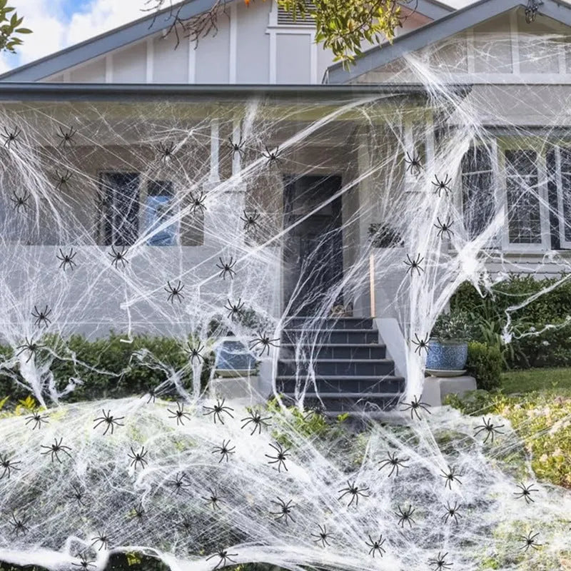 White cotton Halloween spider web decoration draped on a surface with scattered plastic spiders.