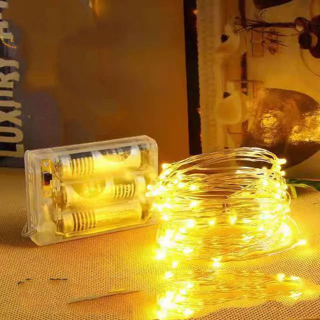 Close-up of flexible copper wire fairy lights with warm white LEDs wrapped around a wooden banister