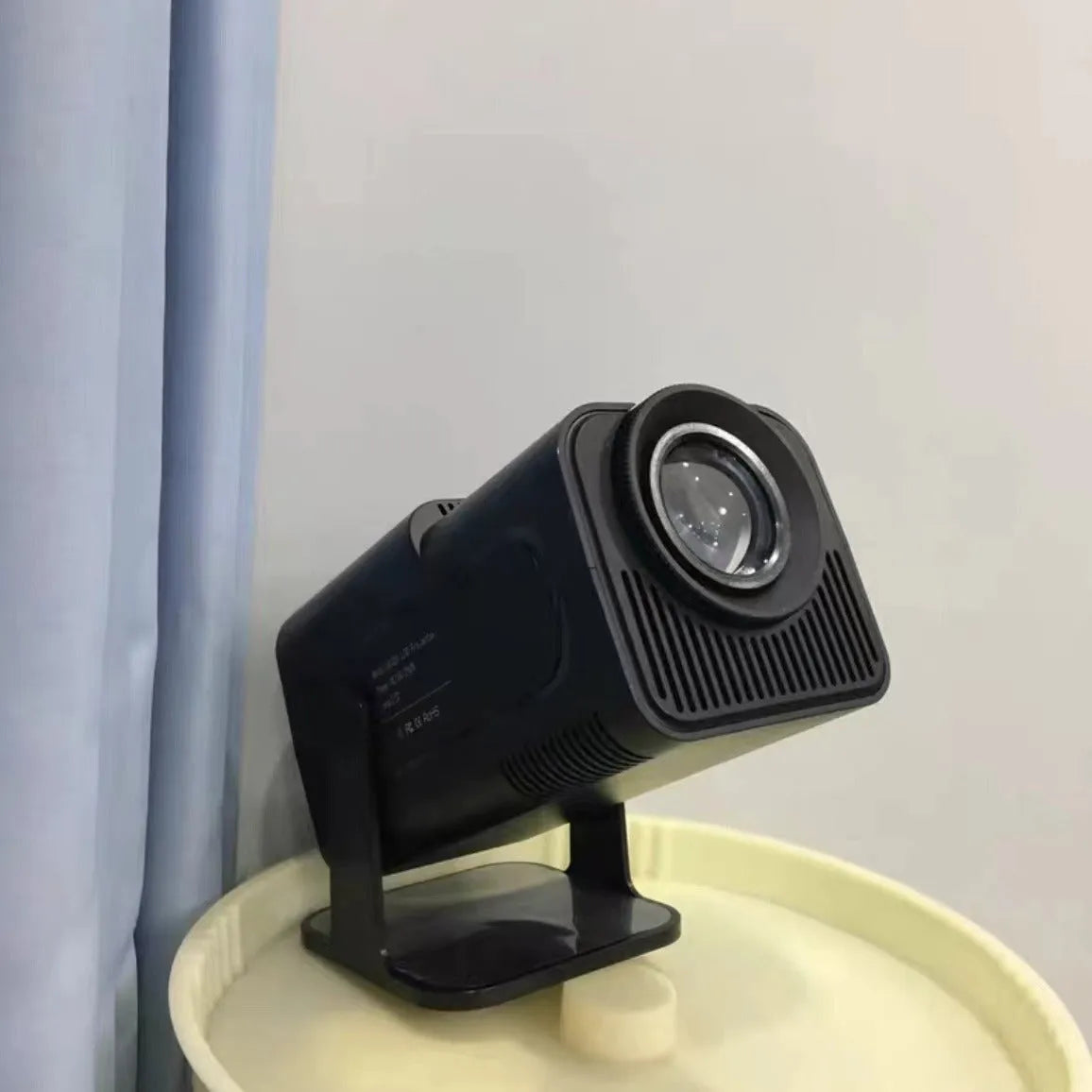 A wireless home projector with a handheld remote on a table, set up for big-screen gaming or movie viewing.