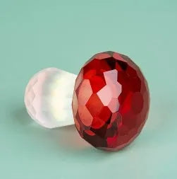Small solid crystal mushroom ornament in modern geometric style on a wooden surface.