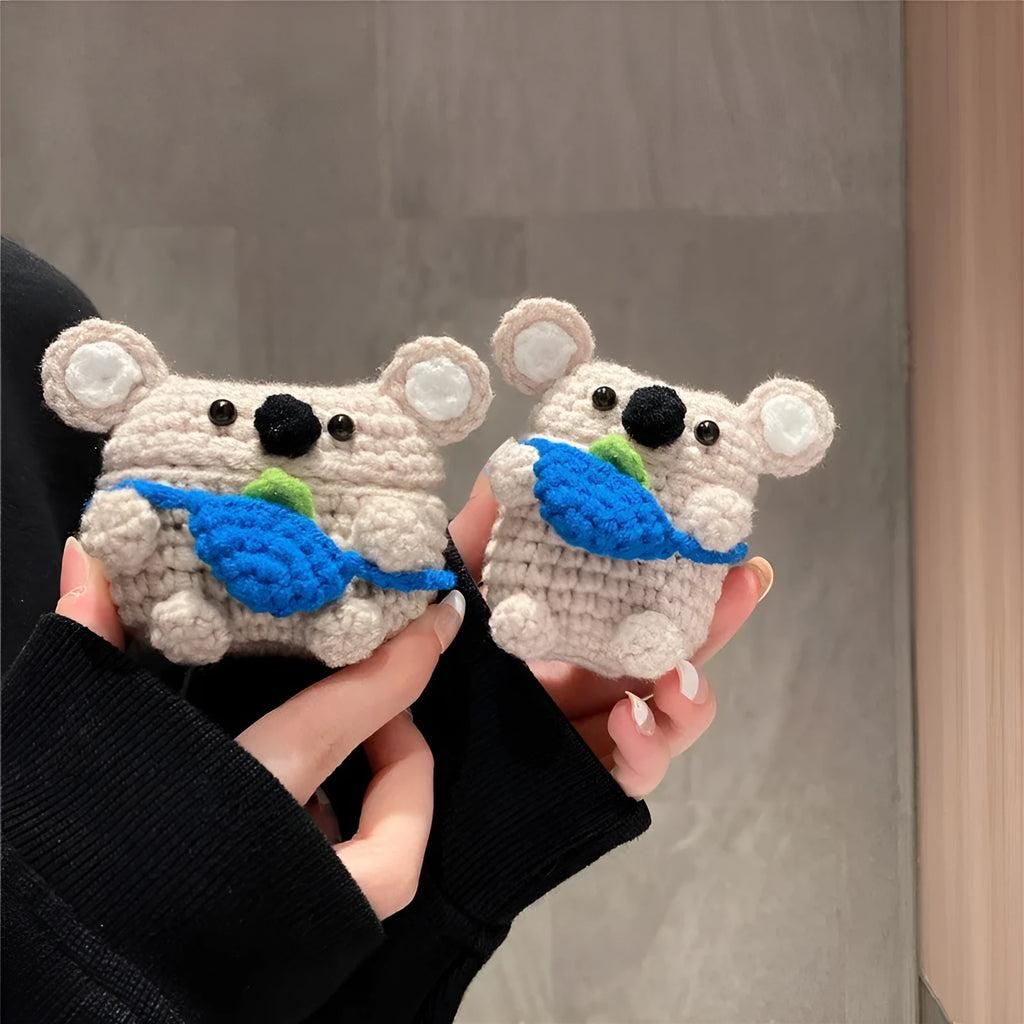 Hand-knitted grey koala bear backpack design earphone cover for Apple AirPods on a table.