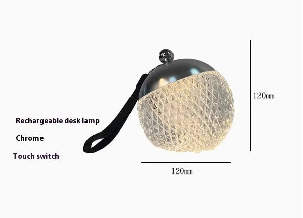 Small portable dimmable night lamp in chrome finish on wooden bedside table