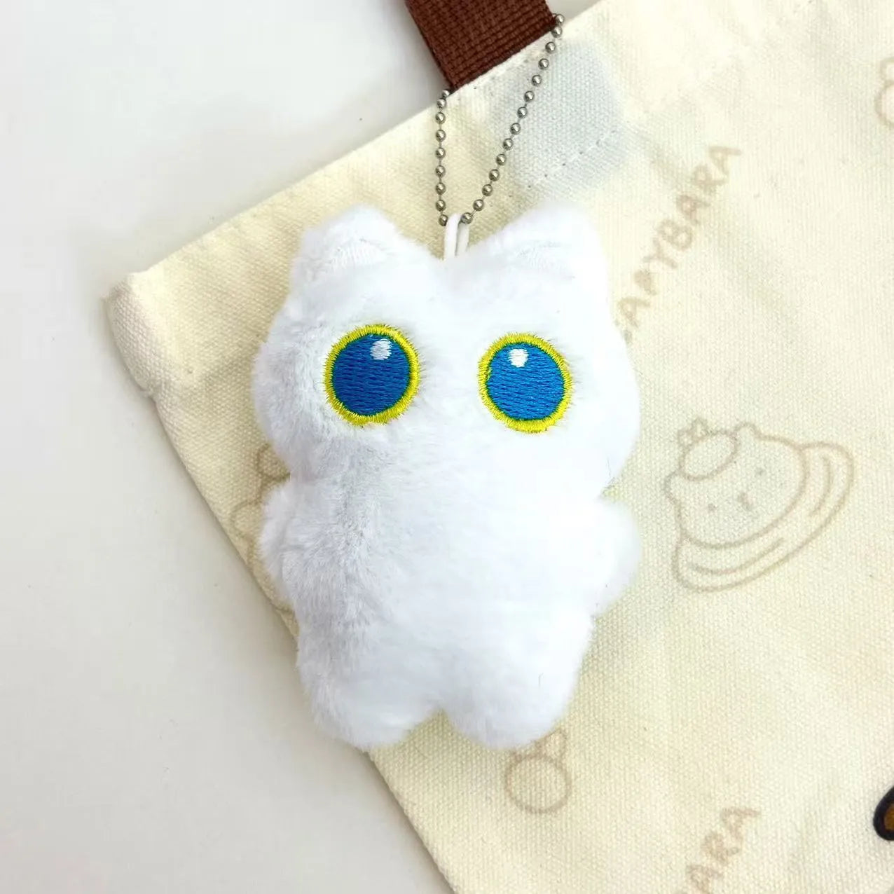Cartoon big eye black cat doll plush with bead necklace as key decoration on a bag