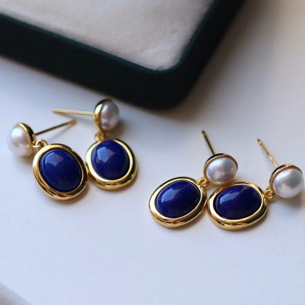 A pair of simple 925 silver earrings featuring a blue lapis lazuli pearl and auspicious pattern detailing.