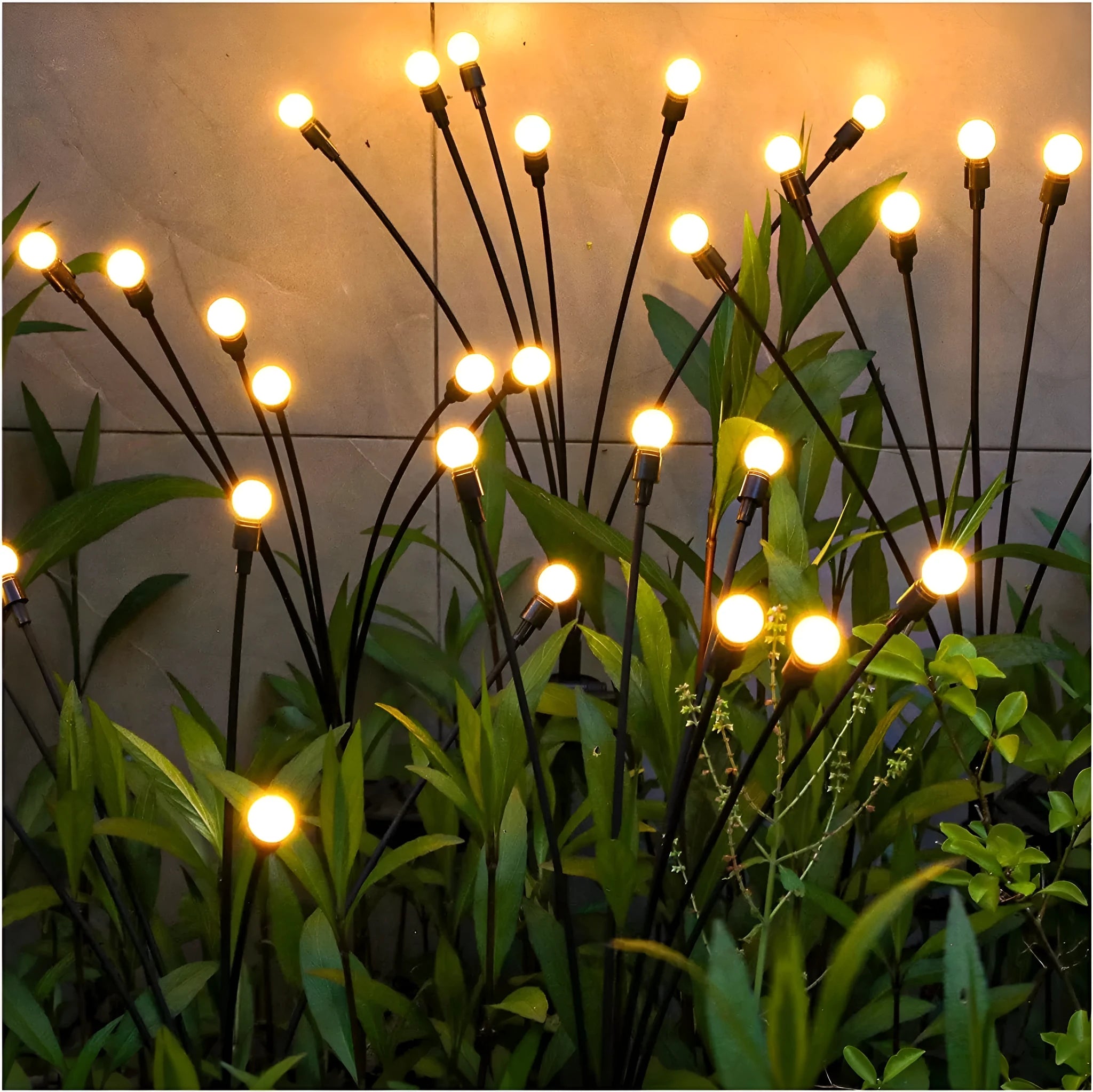 Solar-powered LED firefly garden stake light with stainless steel ground plug illuminated at dusk.