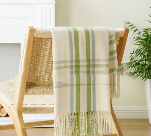 Acrylic chenille plaid throw blanket with tassel trim in gray and white geometric pattern on sofa