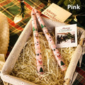 Cylindrical Christmas printed paraffin candle in bright red, 2.2 x 25 cm, on a wooden table