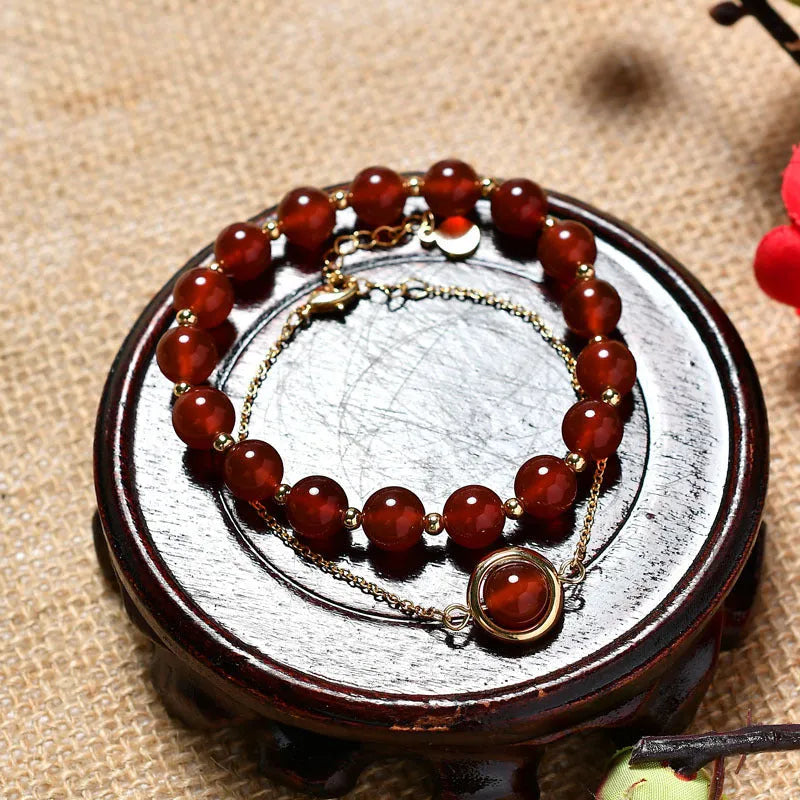 Close-up of a women's double-layer copper bracelet with lucky beads and an electroplated gold finish in a strawberry quartz colour.