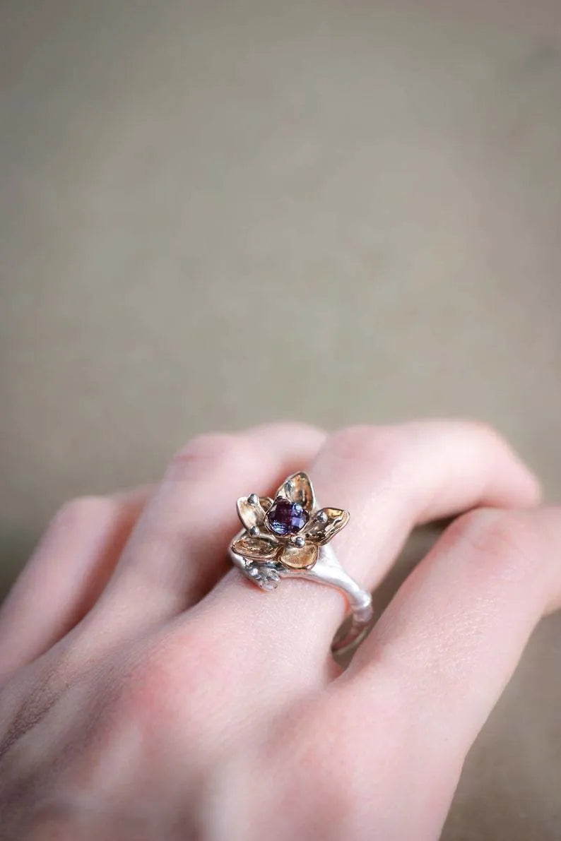 Geometric silver two-tone women's ring with open floral detail on a plain background.