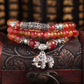 A handmade bracelet with geometrically cut watermelon crystal beads and a red Chinese knot closure on a white background.