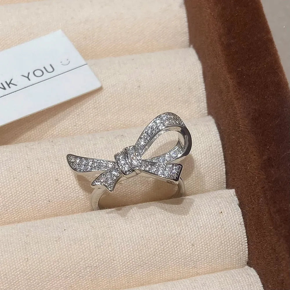 Gold miniature zircon inlaid bowknot ear stud and matching ring set on display