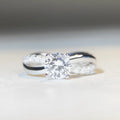 Geometric silver moissanite ring with a 1 karat stone and twisted band.