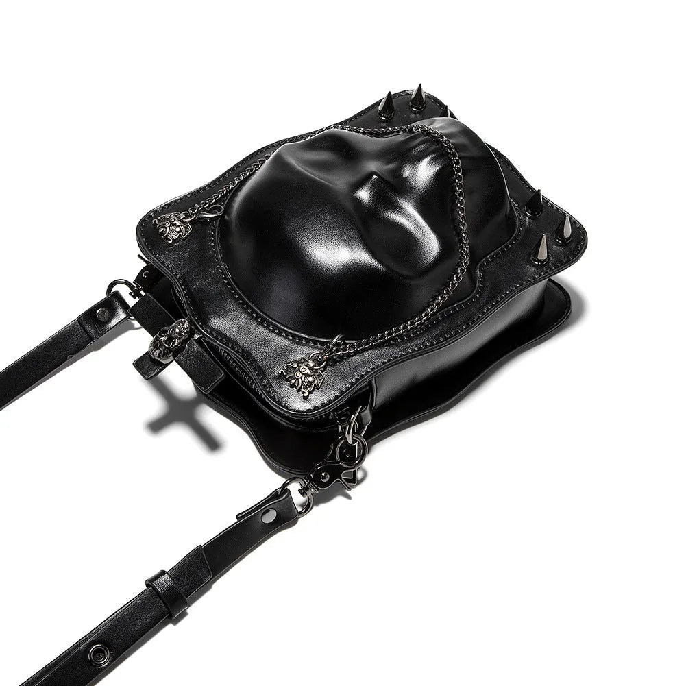 Black vertical square crossbody bag with embossed skull design, chain strap, and metal rivets.