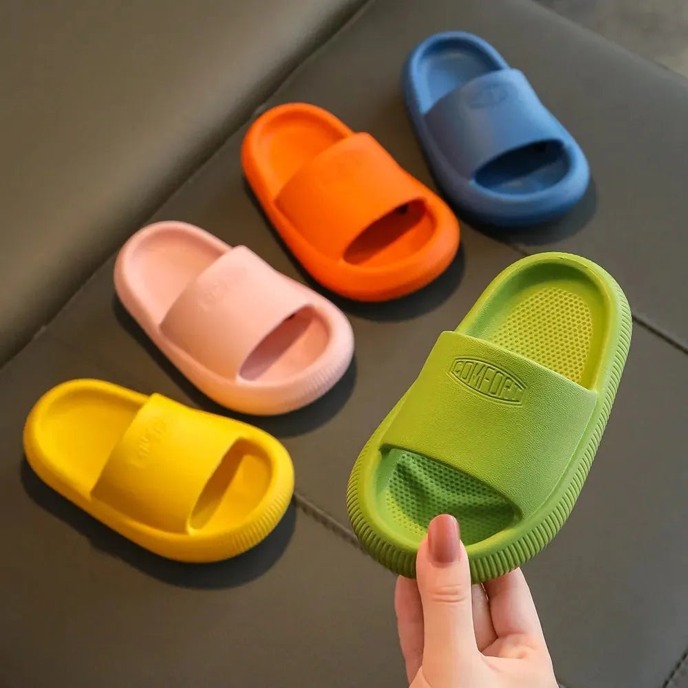 A pair of bright blue, one-piece EVA children's slippers with a textured non-slip sole, shown on a wooden floor.