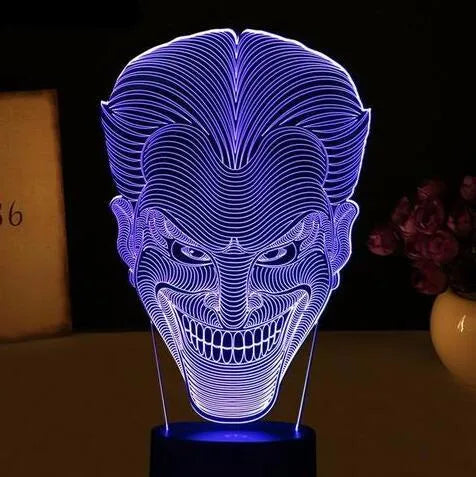 A 3D acrylic LED lamp on a base, showing a colourful gradient light effect, with a remote control beside it.