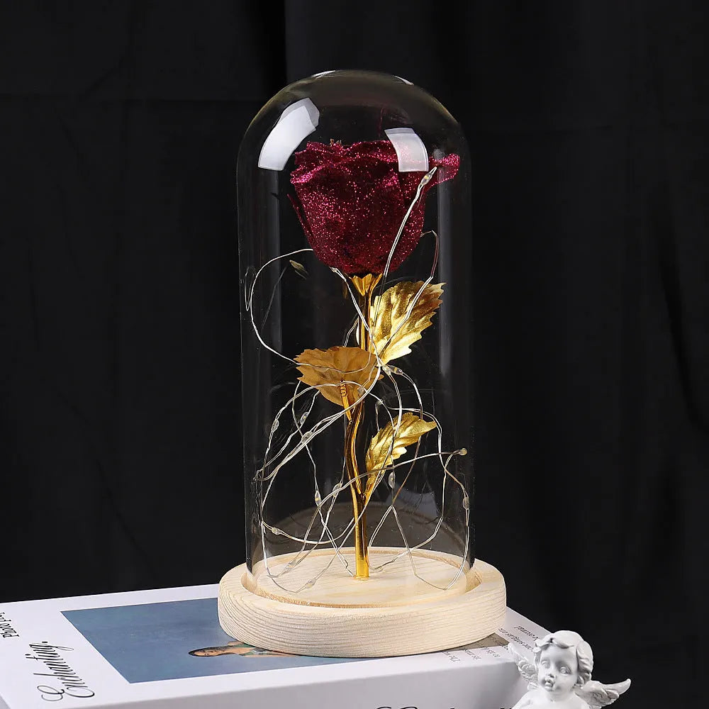 Red eternal rose in glass cover with warm white LED strip lit on dark surface