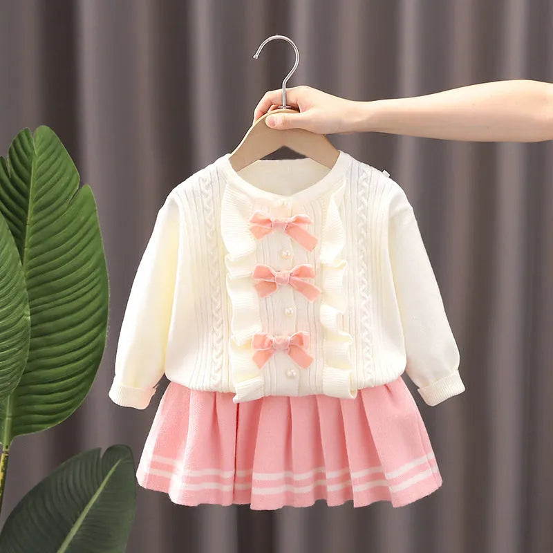 Knitted baby girl two-piece skirt suit in pink with bow detail and long sleeves, autumn wear