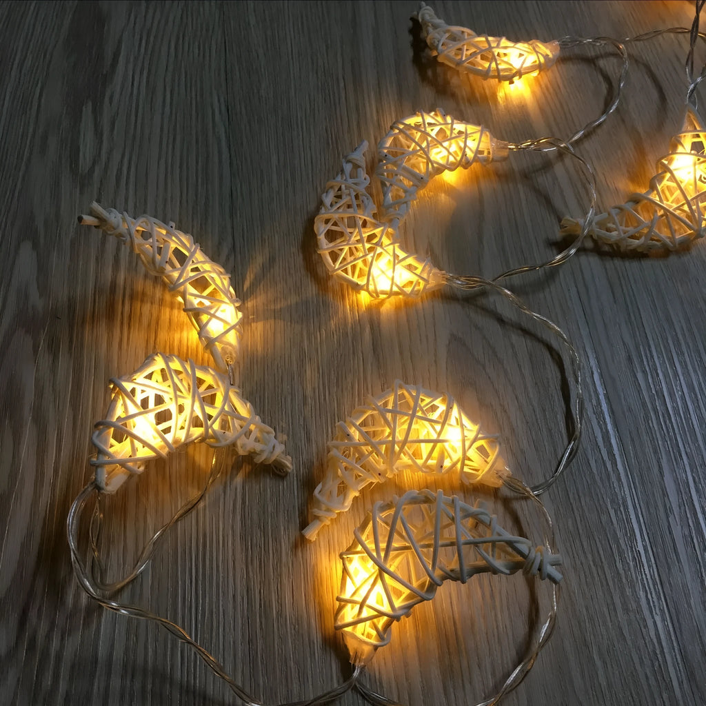 Handwoven rattan moon pendant fairy light chain with warm white glow on a dark background