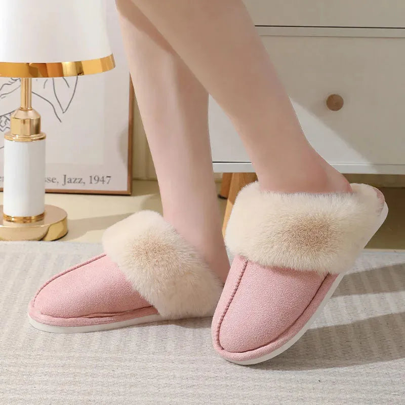 Brown plush indoor slippers for women with a non-slip PVC sole on a wooden floor.