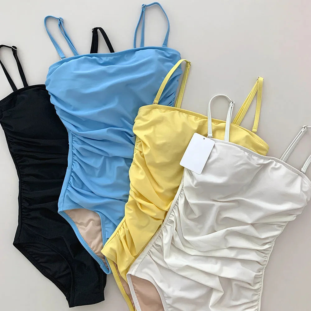 Women's sling style one-piece swimsuit with belly pleating in solid colour.