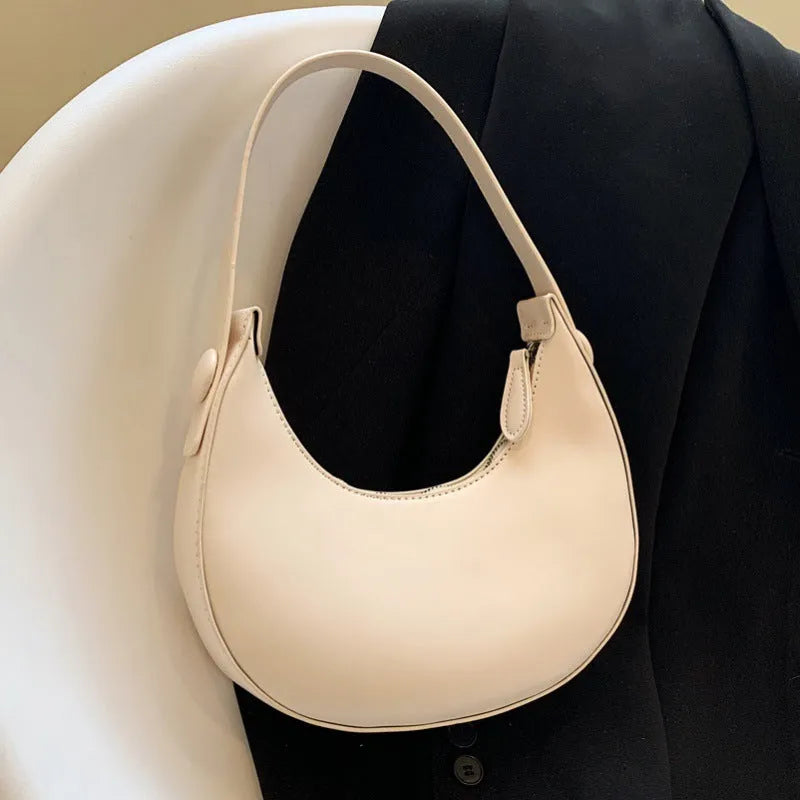 Retro-style dumpling-shaped PU leather shoulder bag in cream yellow showing front sandwich pocket.