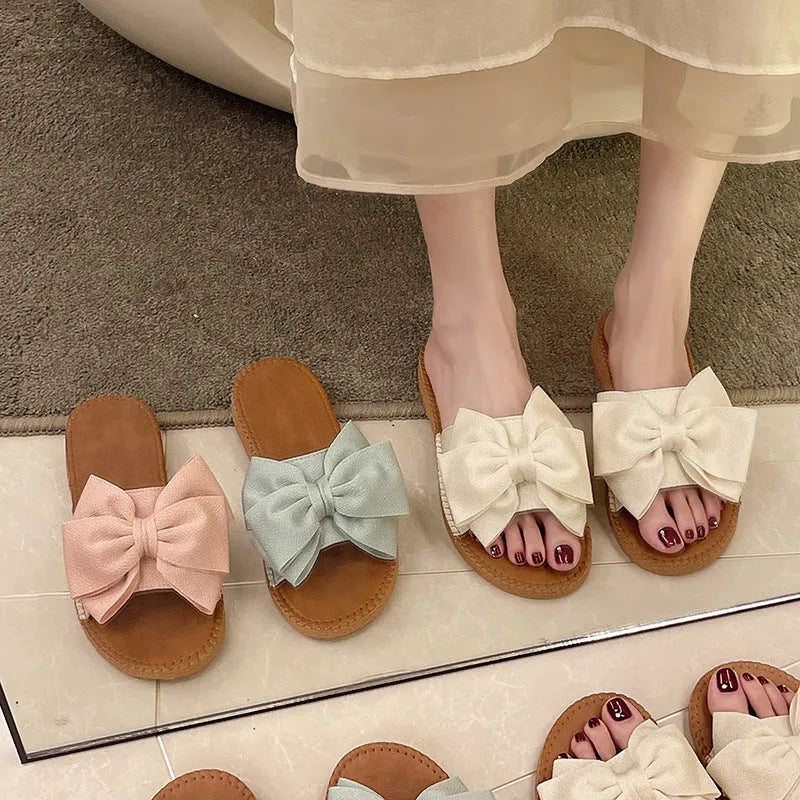 Women's beige suede slip-on sandals with a bow detail and soft rubber sole