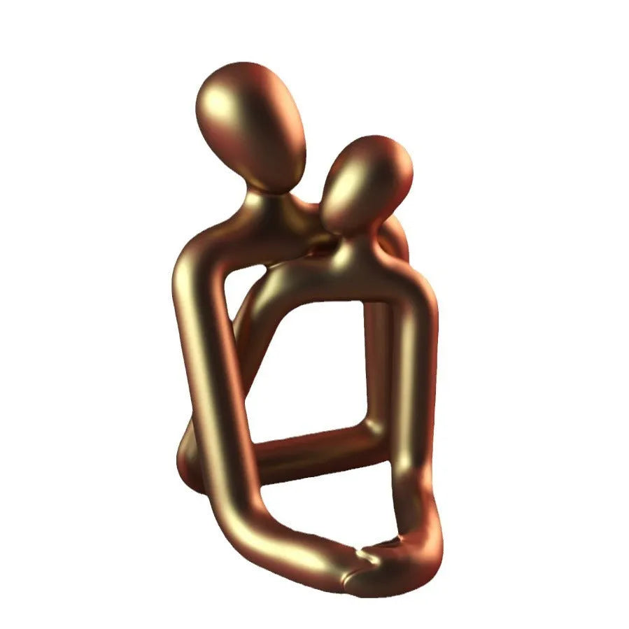 Modern loving couple resin statue in milky white or gold colour on a desk.