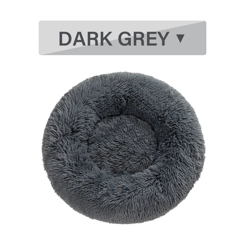 A fluffy, round donut-shaped dog bed with a raised rim in long plush fabric.